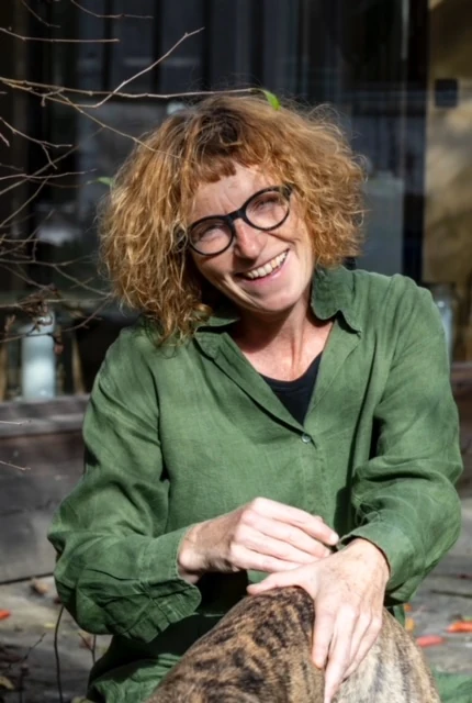 Porträt von Manuela Lasnik, lächelnd in grüner Bluse.